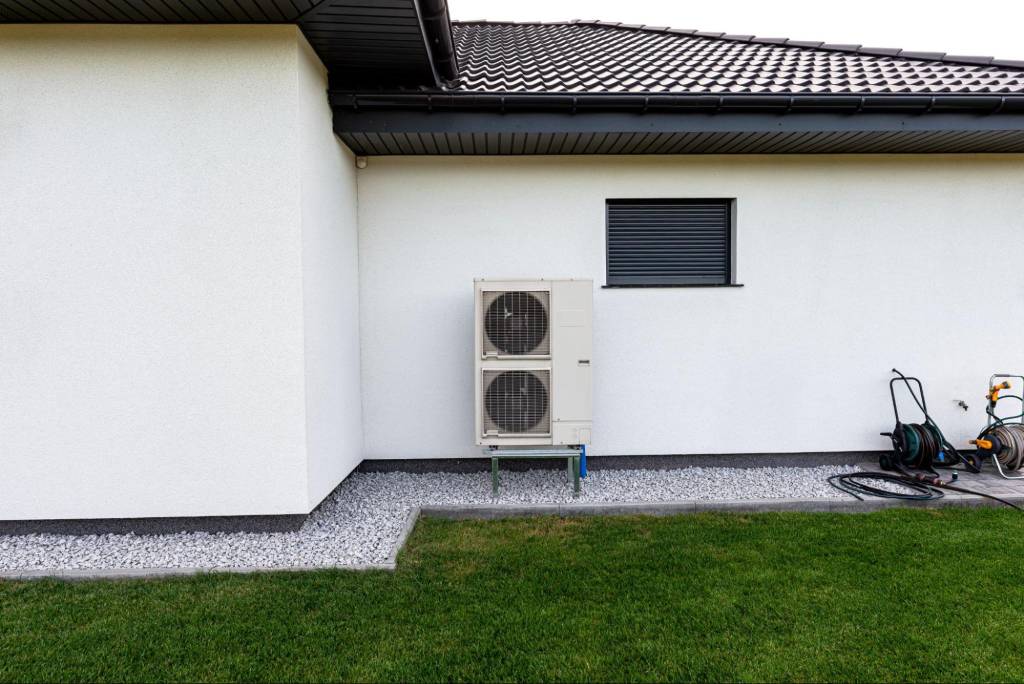 Two outdoor heat pump units stacked vertically in front of a house
