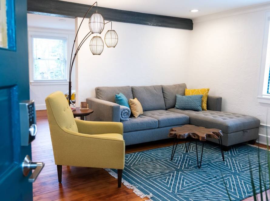 Stylish blue-themed reception area with a yellow lounge chair, pendant standing lamp, and geometric table