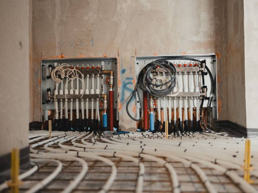 Hydronic underfloor heating manifold installed within a concrete floor, distributing heated water to radiant floor loops