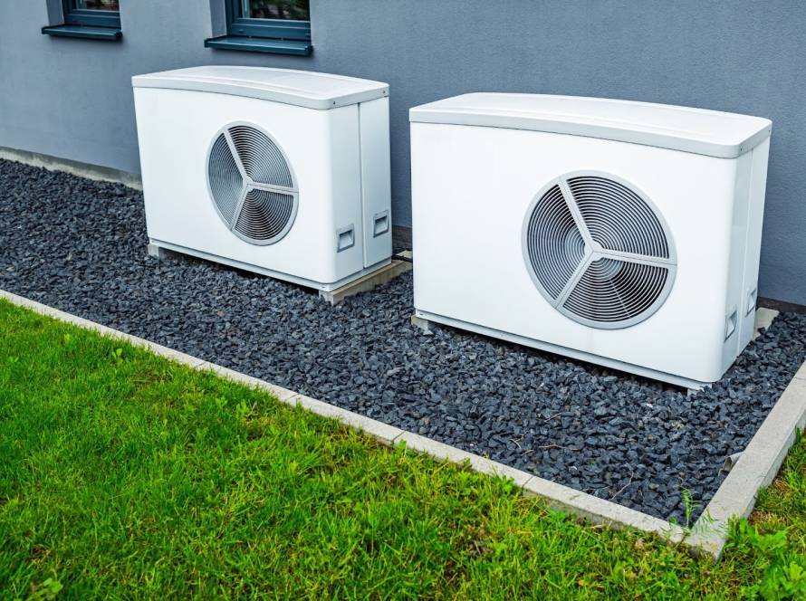 Two modern air-source heat pumps installed outside a contemporary city home